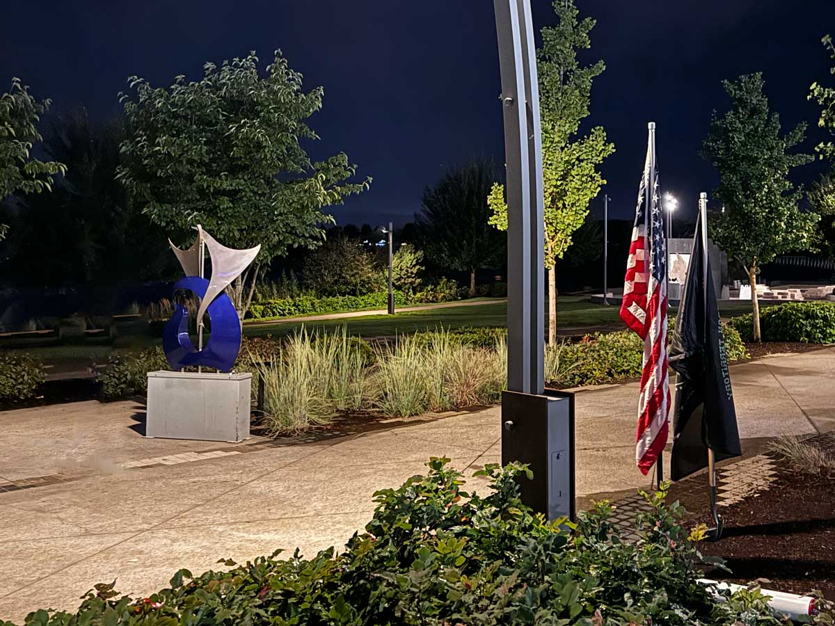 Picture of the Petting Zoo meeting place with the "Dancing Fish" sculpture and two shovel flags.